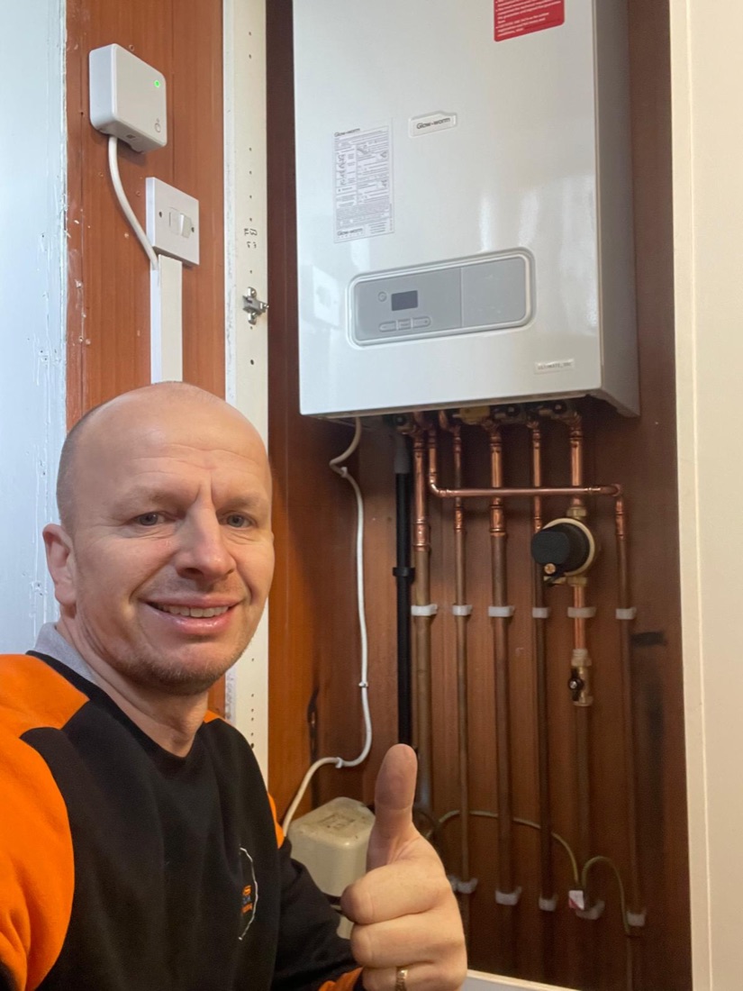 A 123-Gas engineer beside a newly installed Glow-worm boiler with tidy copper pipework, giving a thumbs up