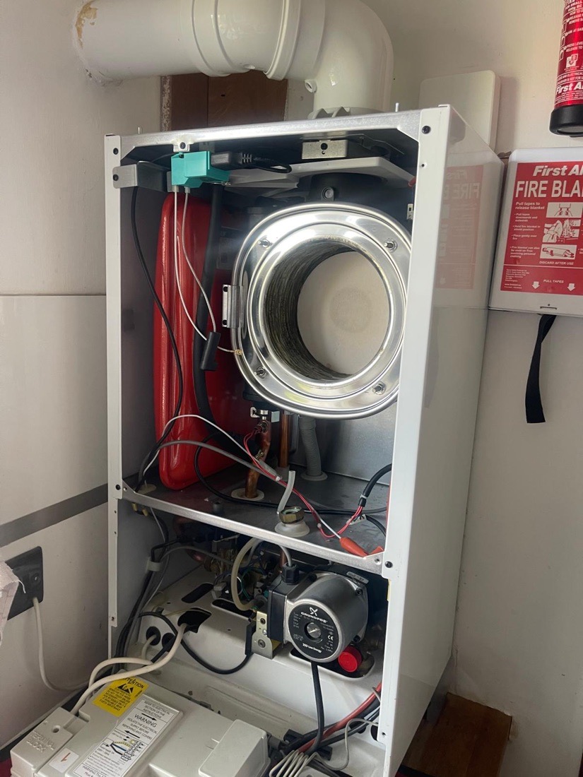 A boiler opened up for diagnosis by a 123-Gas engineer, with the casing off and the heat exchanger and pump exposed