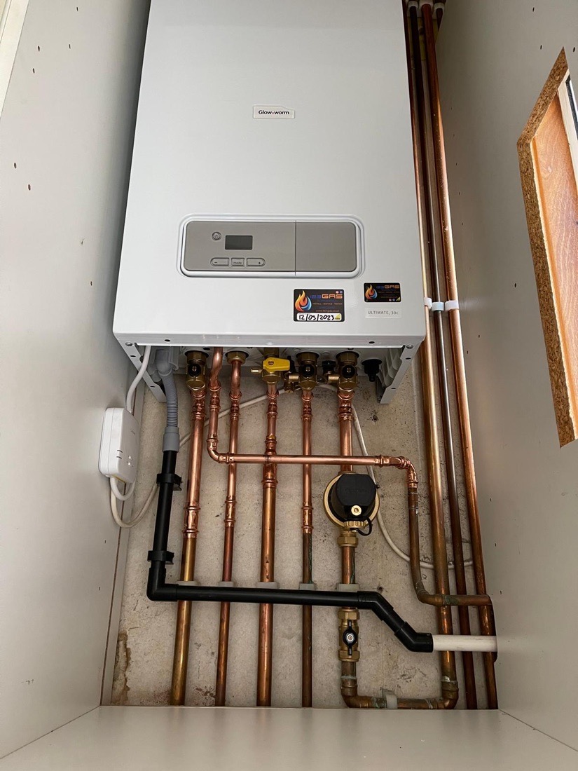 A Glow-worm combi boiler installed in a cupboard above tidy soldered copper pipework