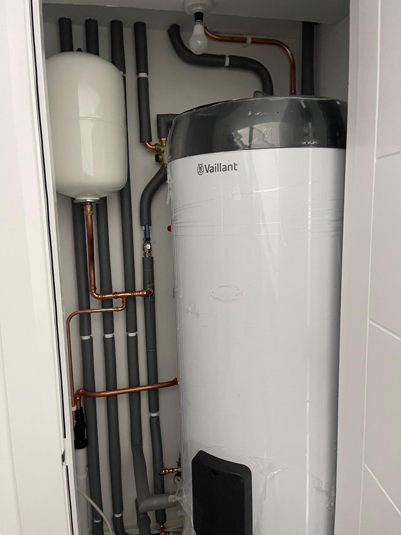 A Vaillant boiler beside an unvented hot water cylinder with labelled pipework