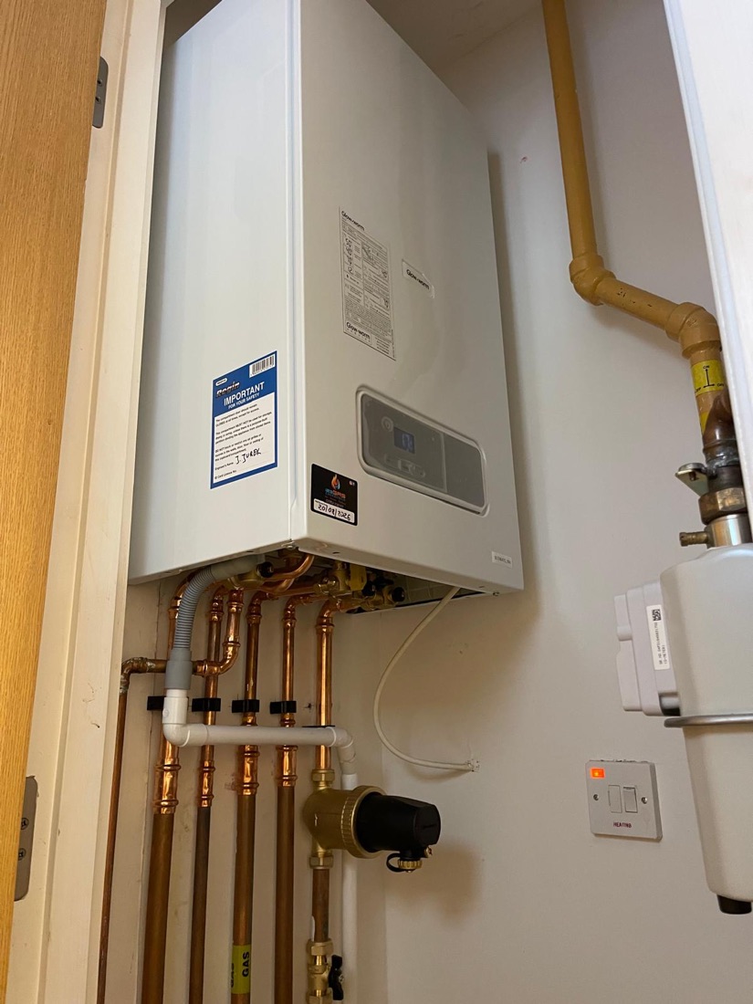 A Glow-worm boiler fitted in a cupboard beside the gas meter, with copper pipework below