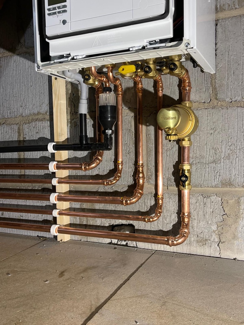 Copper pipework and brass valves clipped neatly to a block wall in a plant room